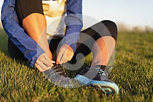 Young woman tying shoelace of sneakers to make outwork training running. Fitness and healthy lifestyle photo