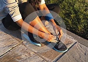 Young woman tying shoelace of sneakers to make outwork training running. Fitness and healthy lifestyle photo