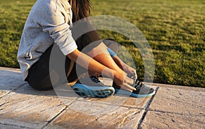 Young woman tying shoelace of sneakers to make outwork training running. Fitness and healthy lifestyle photo