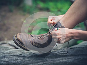 Young woman tyoing her boots in forest