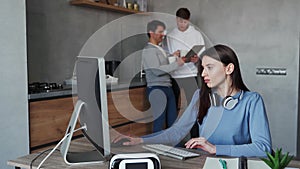 Young woman typing on computer while her colleagues talking on background. Team working concept