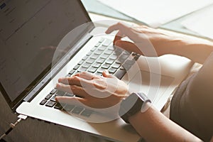 Young woman typing on a laptop keyboard. Close-up details. Girl`s hands. Working online. Freelance concept. Shop on the couch.