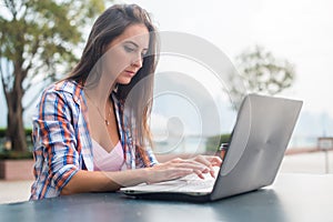 Young woman typing on a laptop studying or working in the park