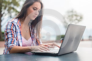 Young woman typing on a laptop studying or working in the park