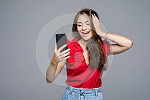 Young woman typing message on smartphone. Beautiful smiling girl using his mobile phone, gray studio background. Communication con