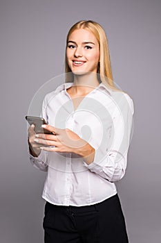 Young woman typing message on smartphone. beautiful smiling girl using his mobile phone, gray studio background. Communication con