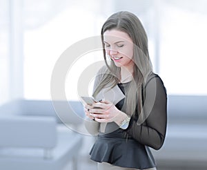 Young woman typing text message on smartphone,while standing in the office