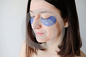 Young woman with under eye patches in her face. Collagen eye mask for puffiness, close-up view. Facial skin care and beauty
