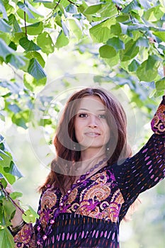 Young woman under green tree in spring park