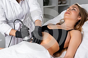 Young woman undergoes ultrasound cavitation procedure for skin tightening