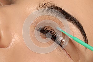 Young woman undergoing eyelash lamination, closeup. Professional service