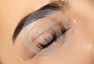 Young woman undergoing eyelash lamination, closeup. Professional service