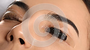 Young woman undergoing eyelash lamination and tinting, closeup