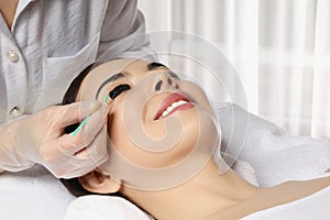 Young woman undergoing eyelash lamination and tinting in salon