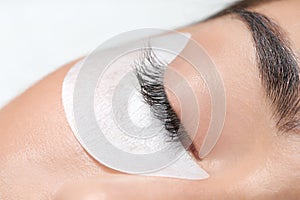 Young woman undergoing eyelashes extensions procedure