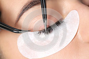 Young woman undergoing eyelashes extensions procedure