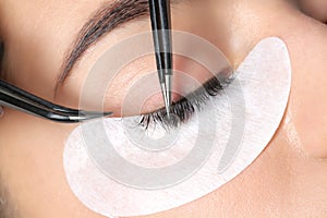Young woman undergoing eyelashes extensions procedure photo
