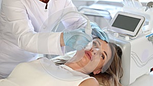 Young woman undergoing hardware facial treatment using cold hammer helping to shrink pores, repair damaged skin and