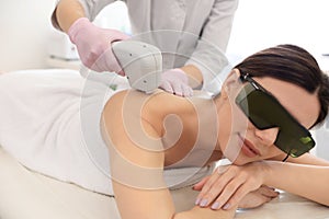 Young woman undergoing laser epilation procedure in salon