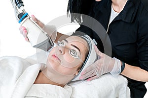 Young woman undergoing a laser skin treatment for non-ablative skin resurfacing to remove wrinkles, acne scars and other facial