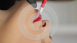 Young woman undergoing procedure of permanent lip makeup in tattoo salon, closeup.