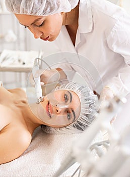 Young woman undergoing radiofrequency facial skin tightening procedure