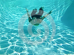 Young woman underwater smiling and swimming in a pool