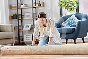 Young woman unfolding carpet at home