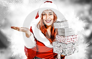Young woman in a uniform of Santa Claus with presents on a blurred snowy winter Christmas day background.