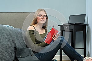Young woman university student with textbooks studying at home
