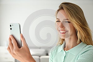 Young woman unlocking smartphone with facial scanner indoors. Biometric verification