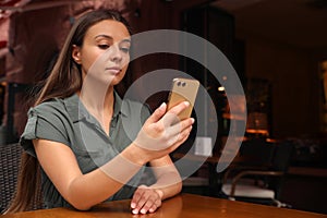 Young woman unlocking smartphone with facial scanner in outdoors cafe. Biometric verification