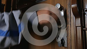 A young woman unlocks and opens a door with metal handle and exits train compartment. A train passenger unlocks door