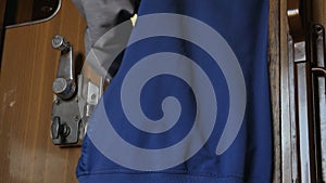 A young woman unlocks and opens a door with metal handle and exits train compartment. A train passenger unlocks door