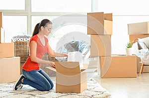 Young woman unpacking box indoors. Moving into new house