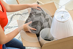 Young woman unpacking box indoors. Moving into new house