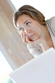 Young woman with upset look in front of laptop photo