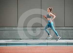 Young woman, urban running and city sidewalk with training, exercise and fitness on road. Street, runner profile and