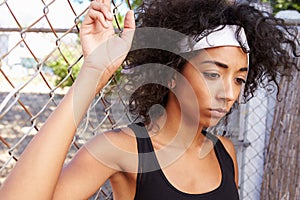 Young Woman In Urban Setting Standing By Fence