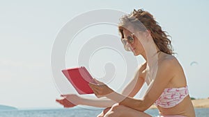 Young woman uses computer tablet on the beach, river bank