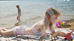 Young woman uses computer tablet on the beach, river bank