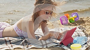 Young woman uses computer tablet on the beach, river bank