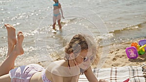 Young woman uses computer tablet on the beach, river bank