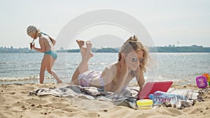 Young woman uses computer tablet on the beach, river bank