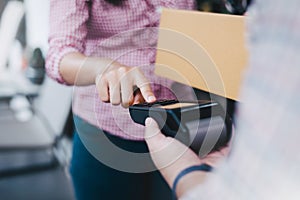 Young woman uses a credit card to pay for goods, NFC payment concept with delivery service