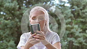 A young woman uses a smartphone in the park Fast typing a message