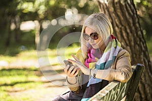 Young woman uses smartphone sitting on bench in the Park.