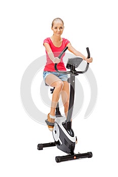 Young woman uses stationary bicycle trainer.