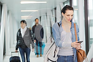 Young woman using cell phone at departure gate