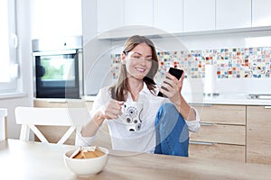 Young woman using cell phone in the kitchen